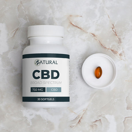 CBD supplement bottle with a softgel on a marble surface