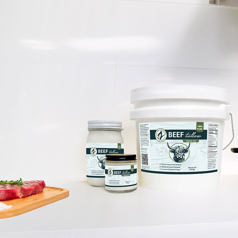 Three containers of beef tallow on a white surface with a wooden cutting board.