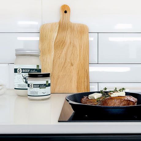 Two jars labeled 'Beef Fellow' on a kitchen counter with a pan of food and a cutting board.