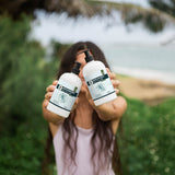Person holding two bottles of New Formulas skincare products outdoors with a blurred natural background