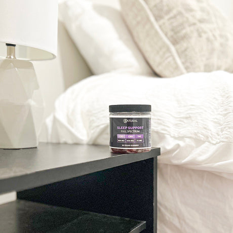 Jar of 'Sleep Support Full Spectrum' on a nightstand next to a bed