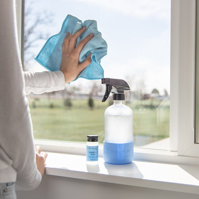 Hempy Home Window and glass concentrate cleaner and spray bottle being used to clean the window